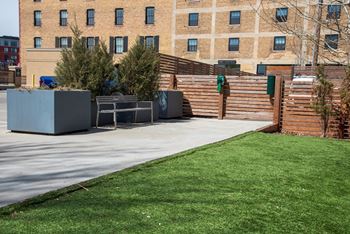 A park with a bench and a tree in front of a building.